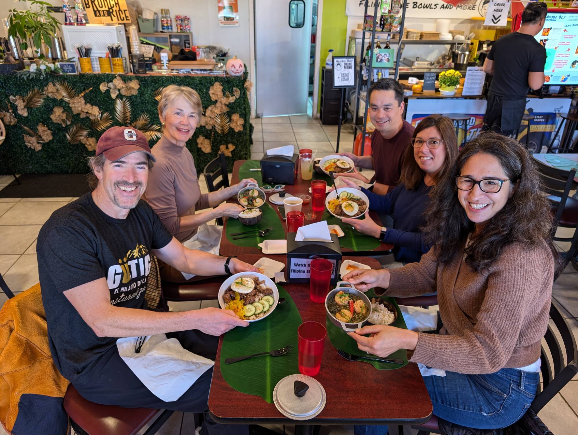 Smiling Faculty showing their dish at a Filipino restaurant